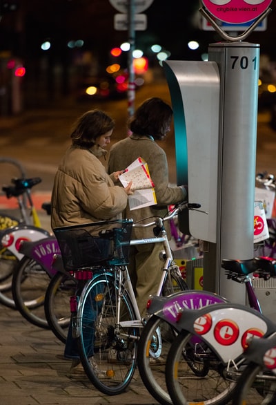 穿着棕色夹克的女人站在自行车旁边